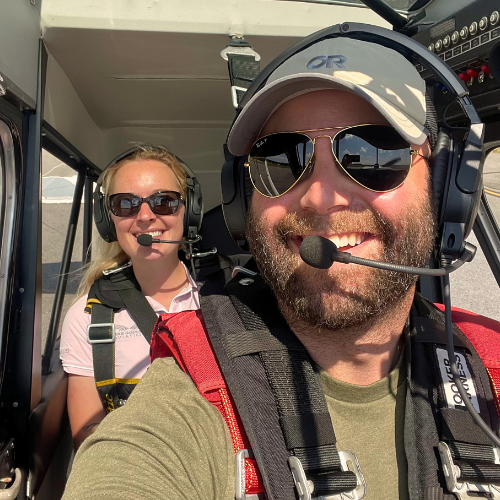 Woman and her instructor smiling in a plane