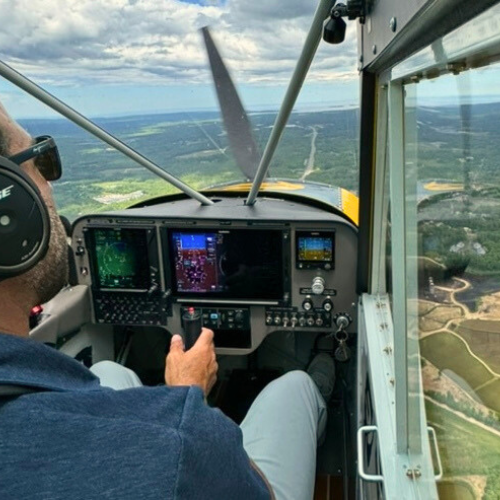 A man flying a plane over grassy plains small image